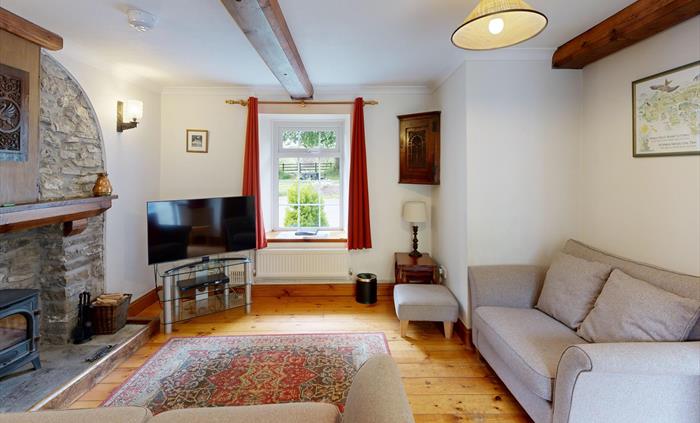 Traditional lounge with two sofas, log burner, wooden floors, and cottage-style decor.
